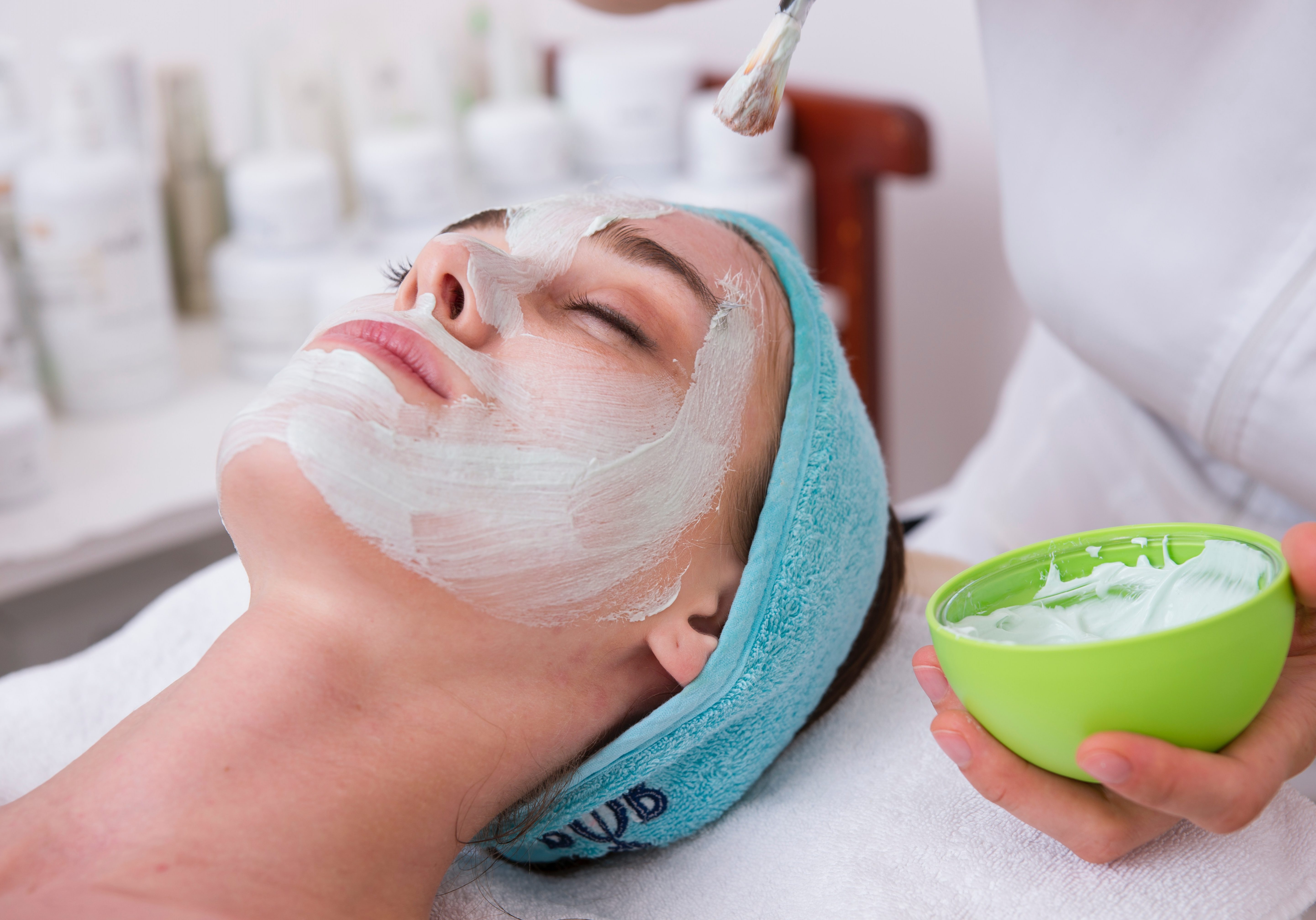 woman lying on blue towel with white cream on face